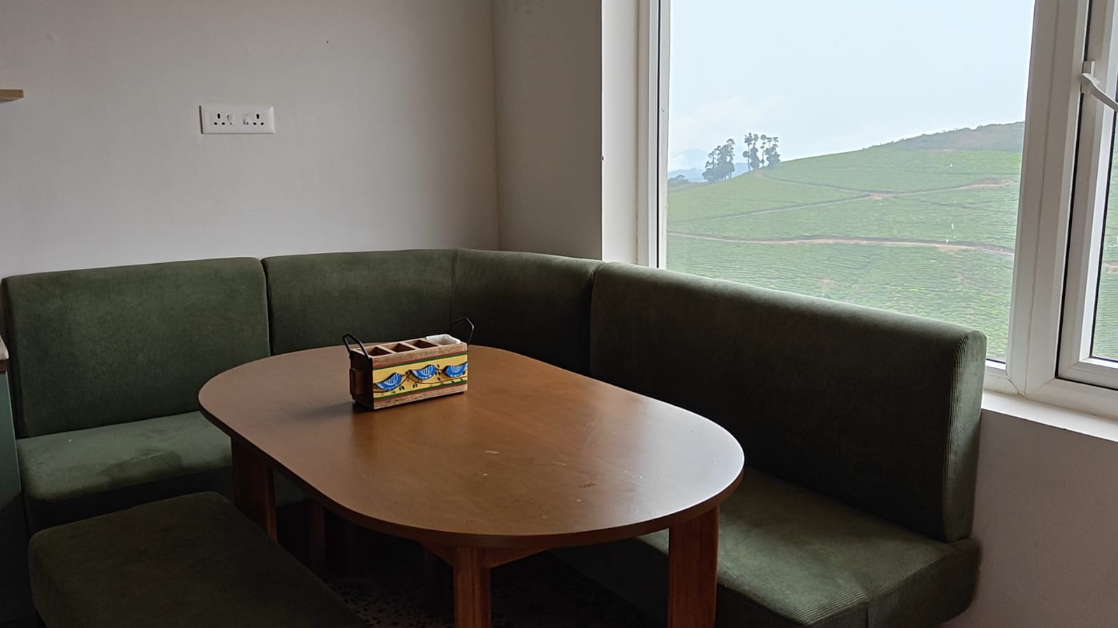 A green banquette booth by the window on the upper floor, set for a meal or a quiet cup of tea with the tea garden hills in view